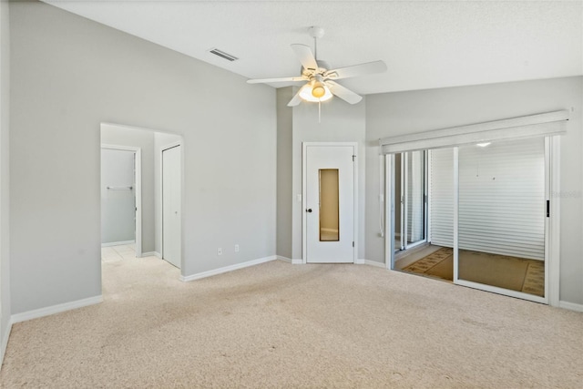 unfurnished bedroom featuring light carpet, a closet, vaulted ceiling, and ceiling fan