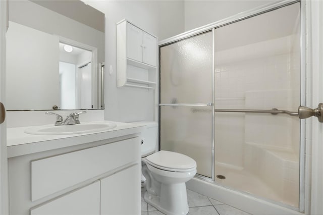 bathroom with toilet, vanity, tile patterned floors, and walk in shower