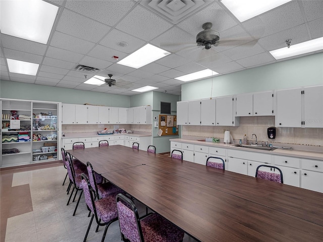 dining area with a paneled ceiling, ceiling fan, and sink