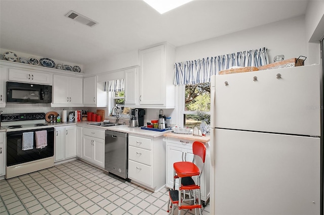 kitchen featuring decorative backsplash, sink, white cabinets, and white appliances