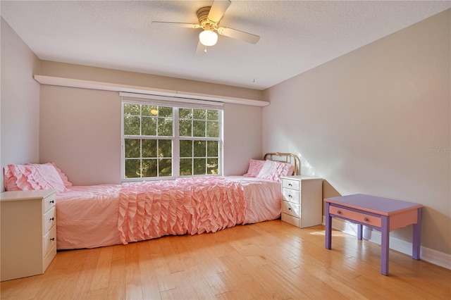 bedroom with ceiling fan, light hardwood / wood-style flooring, and a textured ceiling