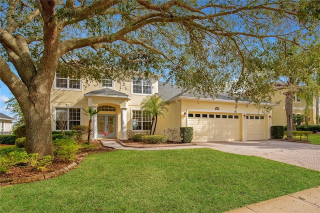 view of front facade featuring a front lawn, a garage, and french doors