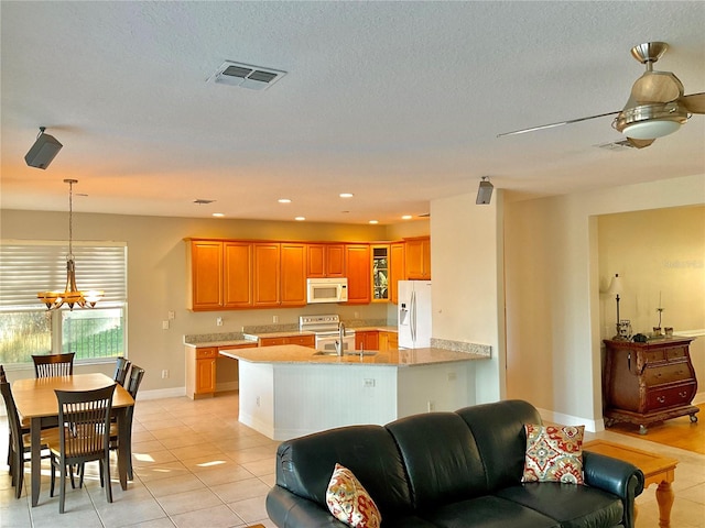 kitchen featuring white appliances, sink, hanging light fixtures, light tile patterned flooring, and kitchen peninsula