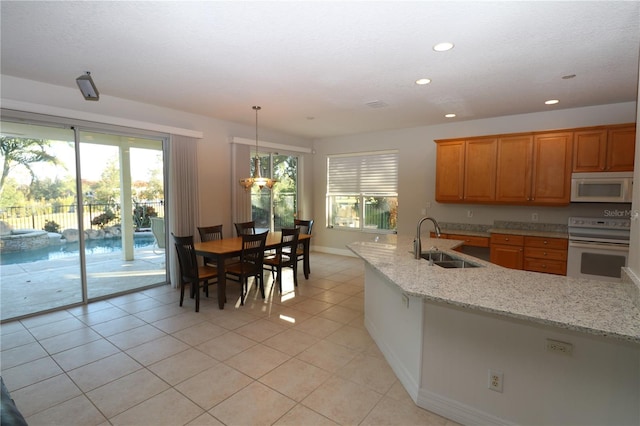 kitchen with sink, light stone counters, decorative light fixtures, white appliances, and light tile patterned flooring