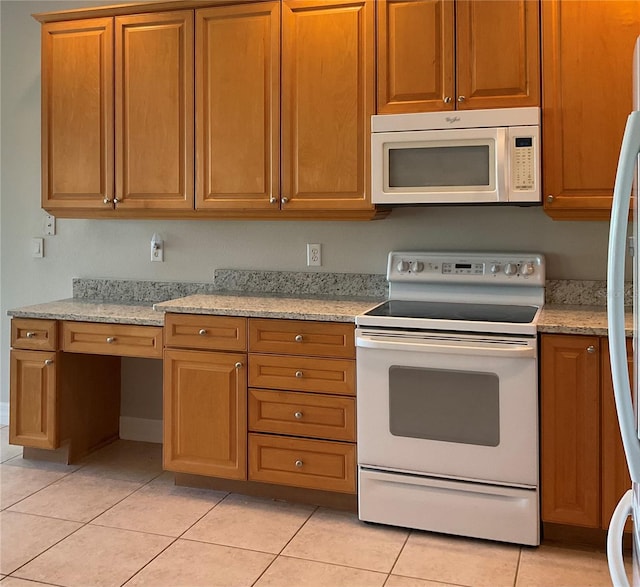 kitchen with light stone counters, light tile patterned floors, and white appliances