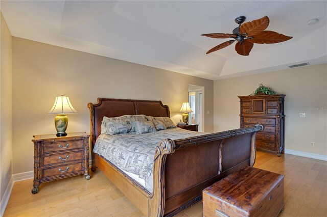 bedroom featuring ceiling fan, light hardwood / wood-style floors, and a raised ceiling