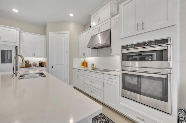 kitchen with white cabinets, black electric stovetop, sink, tasteful backsplash, and stainless steel double oven