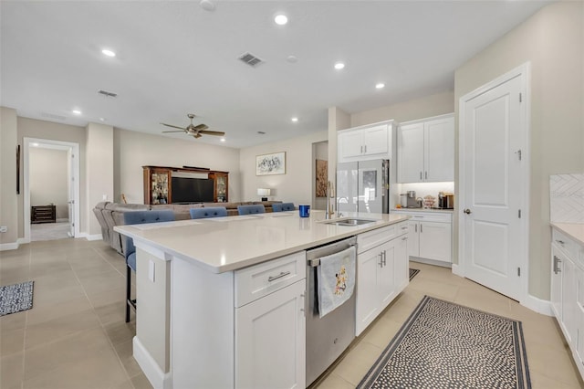 kitchen featuring appliances with stainless steel finishes, ceiling fan, light tile patterned floors, white cabinets, and an island with sink