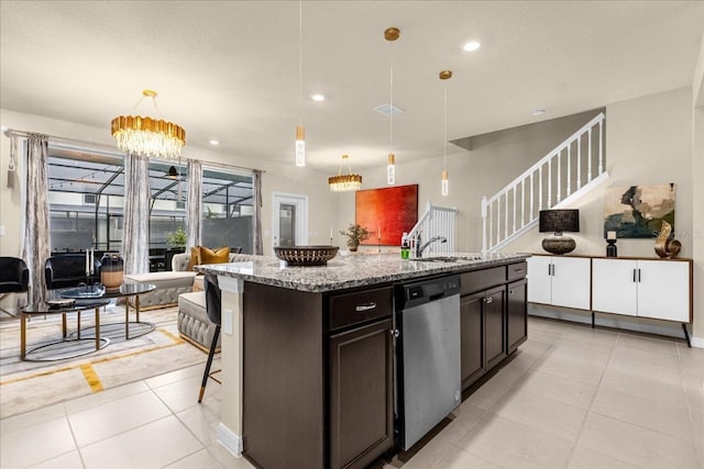 kitchen featuring light stone countertops, pendant lighting, an inviting chandelier, dishwasher, and an island with sink