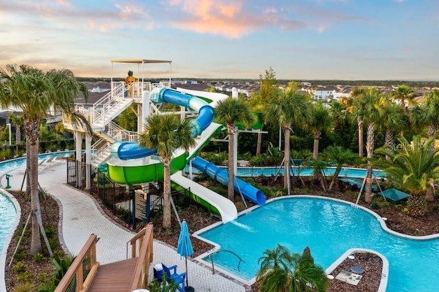 pool at dusk featuring a water slide