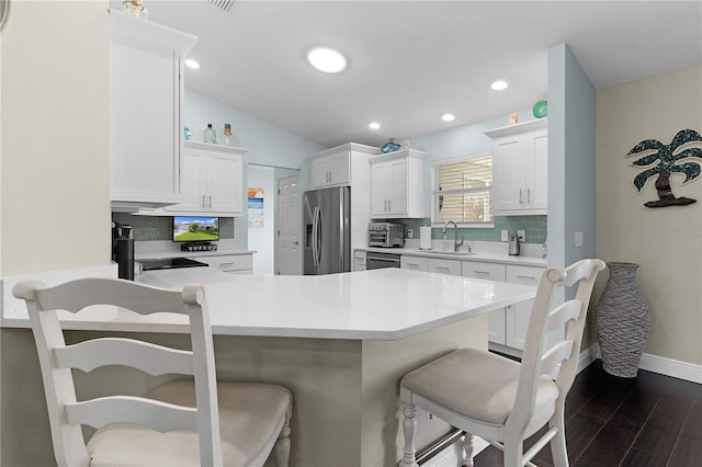 kitchen with decorative backsplash, dark hardwood / wood-style flooring, white cabinetry, and stainless steel appliances