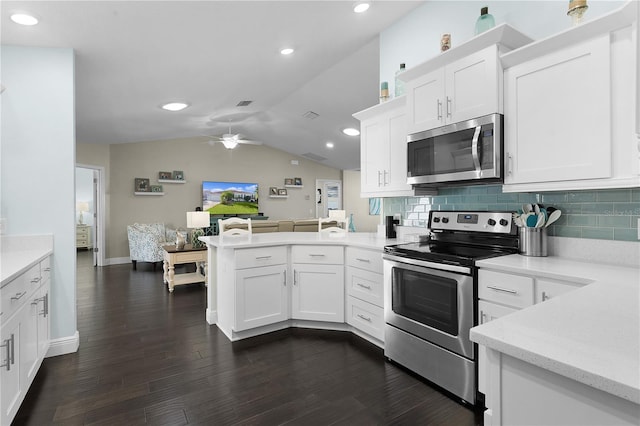 kitchen with dark hardwood / wood-style floors, white cabinetry, kitchen peninsula, and appliances with stainless steel finishes