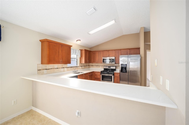 kitchen featuring sink, vaulted ceiling, light tile patterned floors, kitchen peninsula, and stainless steel appliances