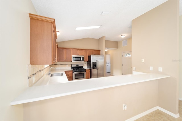 kitchen featuring kitchen peninsula, sink, appliances with stainless steel finishes, and vaulted ceiling