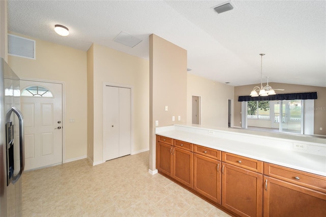 kitchen featuring stainless steel fridge, ceiling fan with notable chandelier, a textured ceiling, pendant lighting, and lofted ceiling