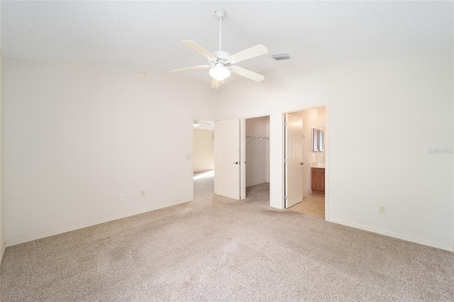 unfurnished bedroom featuring ensuite bathroom, ceiling fan, a spacious closet, light colored carpet, and a closet