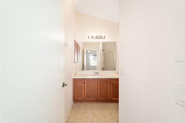 bathroom featuring tile patterned flooring, vanity, a shower with shower door, and lofted ceiling