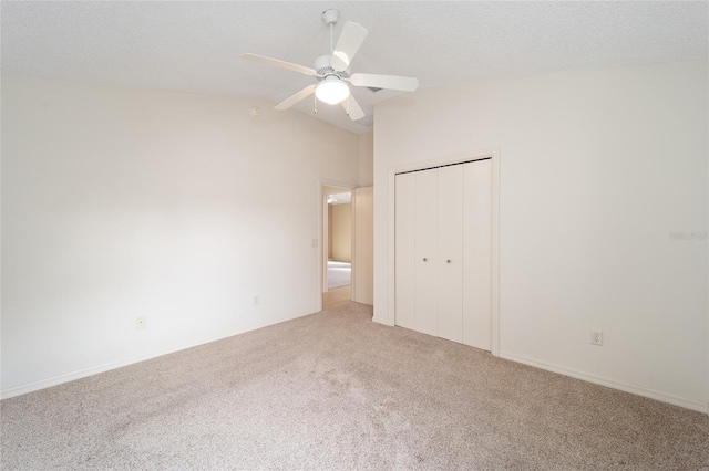 unfurnished bedroom with ceiling fan, carpet floors, a textured ceiling, lofted ceiling, and a closet