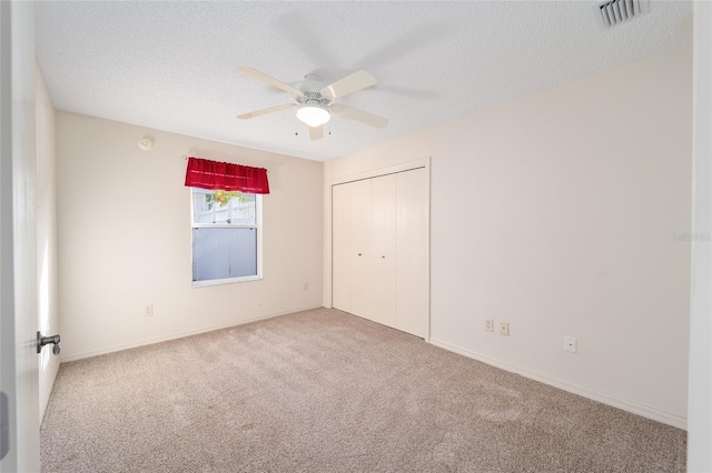 unfurnished bedroom with ceiling fan, a closet, carpet, and a textured ceiling