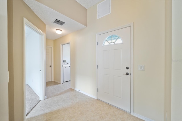 foyer entrance featuring a textured ceiling and light tile patterned flooring