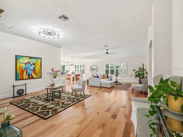 living room with ceiling fan, wood-type flooring, and a textured ceiling