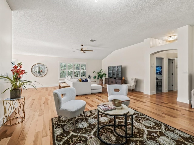 living room featuring wood-type flooring, a textured ceiling, ceiling fan, and lofted ceiling