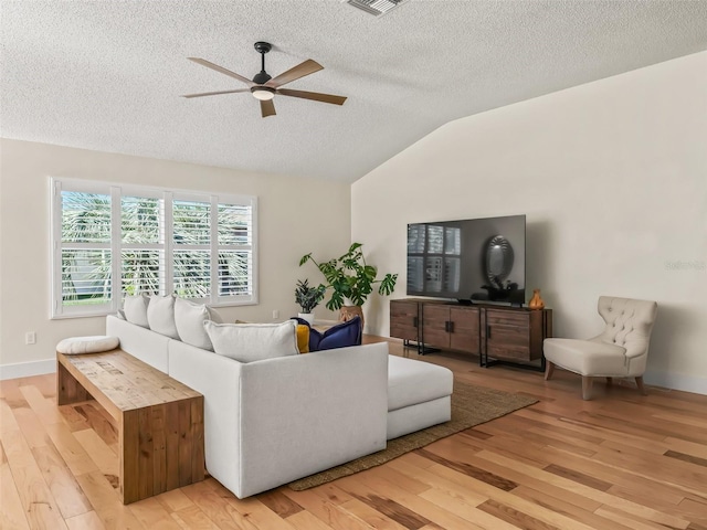 living room with a textured ceiling, light hardwood / wood-style floors, vaulted ceiling, and ceiling fan