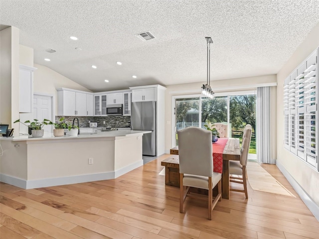 kitchen featuring light hardwood / wood-style flooring, stainless steel appliances, and decorative light fixtures