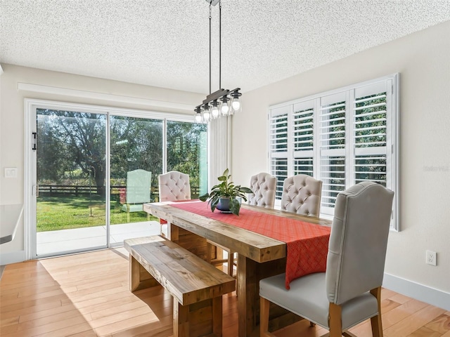 dining area featuring a textured ceiling and light hardwood / wood-style flooring