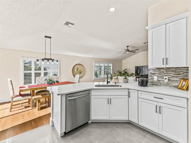 kitchen featuring white cabinetry, sink, hanging light fixtures, stainless steel dishwasher, and vaulted ceiling