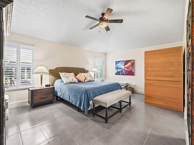 bedroom featuring multiple windows, ceiling fan, tile patterned flooring, and a textured ceiling