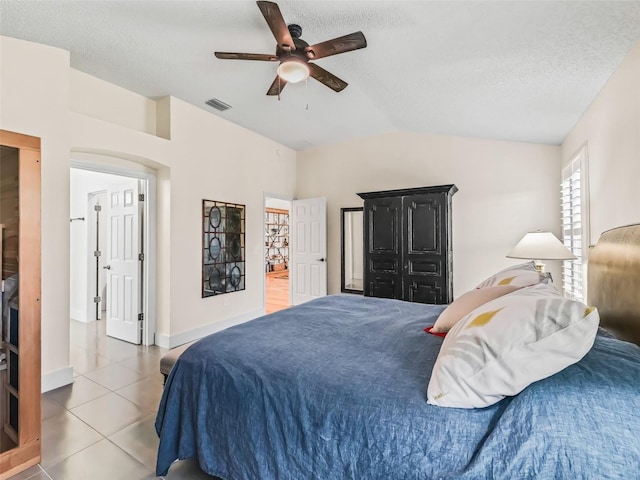 bedroom with tile patterned flooring, a textured ceiling, vaulted ceiling, and ceiling fan