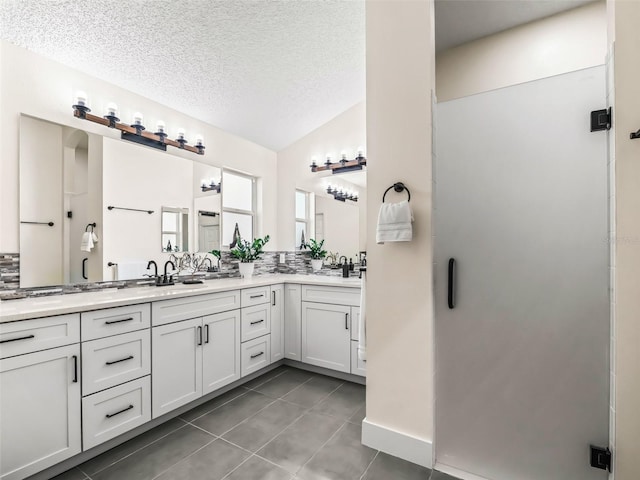 bathroom featuring tile patterned floors, an enclosed shower, vanity, a textured ceiling, and vaulted ceiling