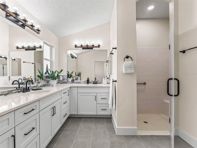 bathroom with tile patterned floors, a textured ceiling, lofted ceiling, vanity, and a shower with shower door