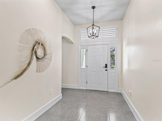 entryway with light tile patterned flooring and a notable chandelier