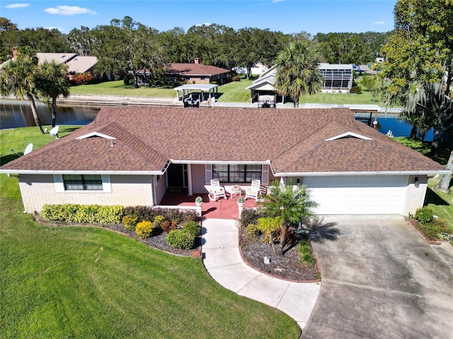 single story home featuring a front lawn, a water view, and a garage