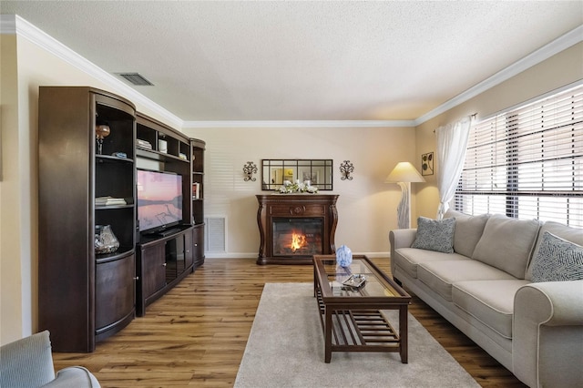 living room with crown molding, wood-type flooring, and a textured ceiling