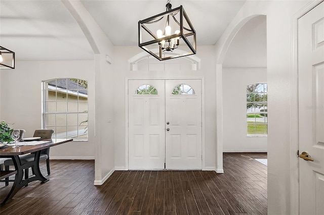 entrance foyer featuring a wealth of natural light, dark wood-type flooring, and a notable chandelier