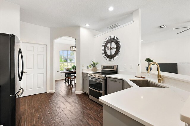 14701 Timucua Pl, Clermont, FL 34711 - kitchen with freestanding refrigerator, double oven range, arched walkways, light countertops, and dark wood-type flooring