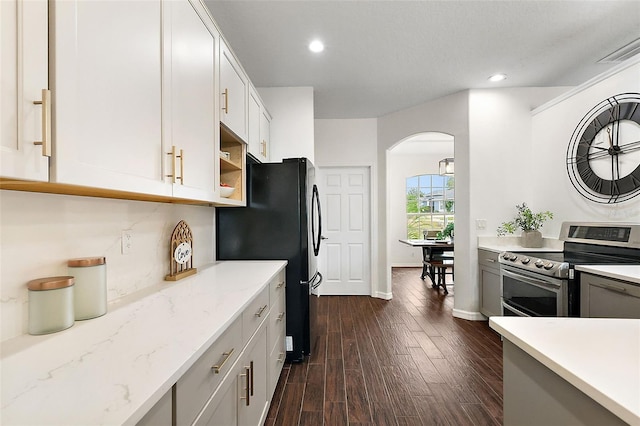 kitchen with white cabinetry, dark wood-type flooring, light stone counters, black fridge, and electric stove