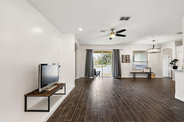 unfurnished living room with ceiling fan with notable chandelier and dark hardwood / wood-style flooring