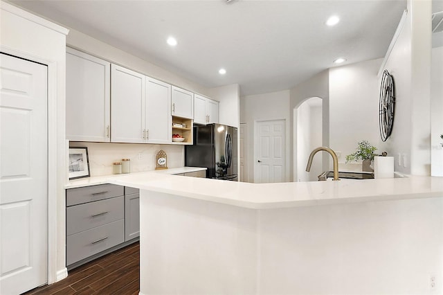 kitchen with gray cabinetry, white cabinets, black refrigerator, dark hardwood / wood-style flooring, and kitchen peninsula