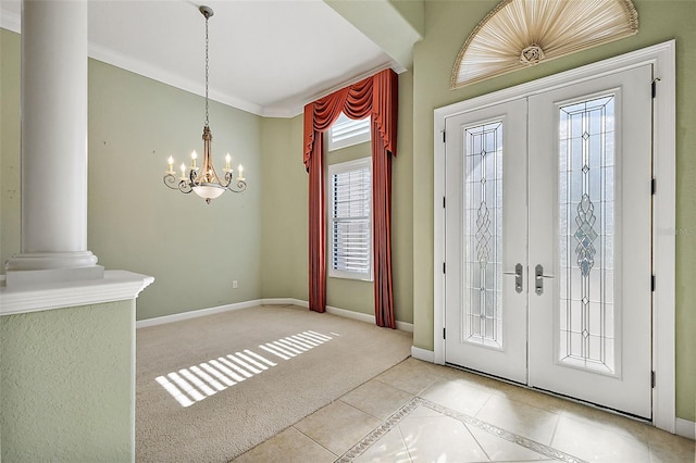 foyer entrance with ornate columns, french doors, light colored carpet, a chandelier, and ornamental molding