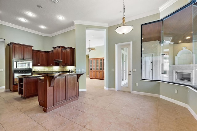 kitchen featuring kitchen peninsula, appliances with stainless steel finishes, a breakfast bar, crown molding, and decorative light fixtures