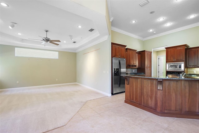 kitchen with ceiling fan, dark stone countertops, ornamental molding, light colored carpet, and stainless steel appliances