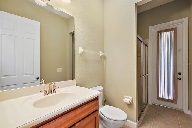 bathroom featuring tile patterned flooring, toilet, an enclosed shower, and vanity