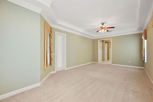 empty room with light colored carpet, a raised ceiling, ceiling fan, and ornamental molding