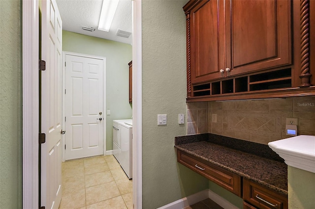 clothes washing area featuring separate washer and dryer, light tile patterned floors, cabinets, and a textured ceiling