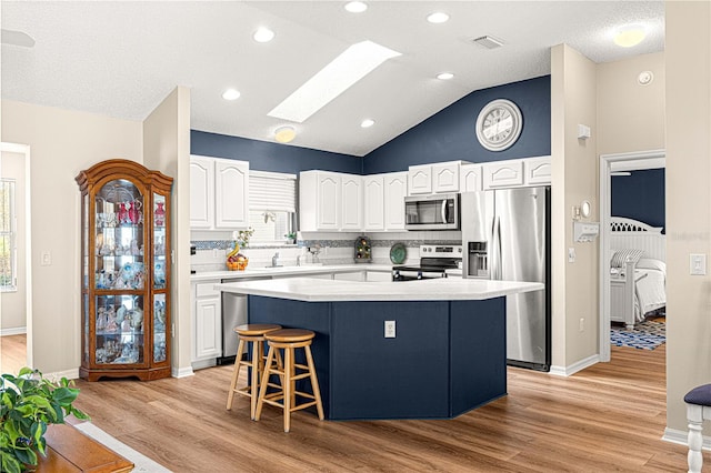 kitchen featuring light hardwood / wood-style floors, a kitchen island, white cabinetry, and stainless steel appliances