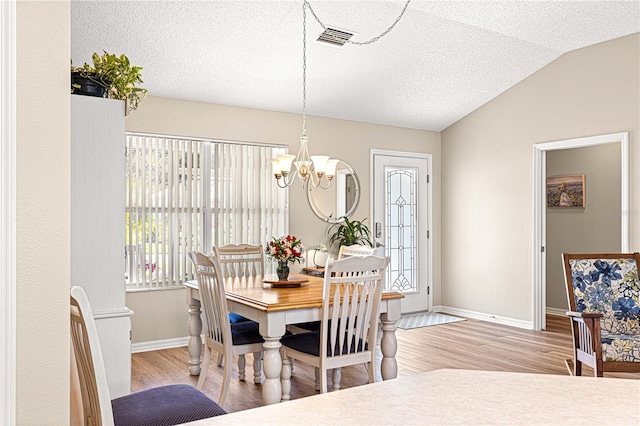 dining area with plenty of natural light, lofted ceiling, and light hardwood / wood-style flooring